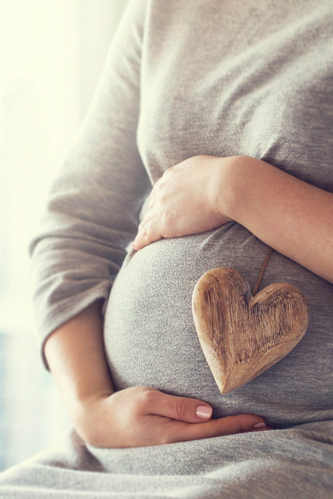 pregnant woman holding heart while touching her belly scaled.jpg
